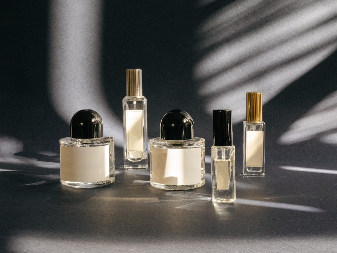 A person thoughtfully selecting a perfume from a variety of bottles on a vanity.