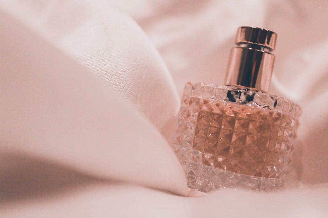 A close-up of a person applying perfume on their wrist, with a soft-focus background of a vanity table adorned with fragrance bottles.