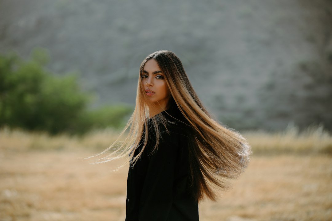 A woman outdoors with long, flowing, straight hair prominently displayed.